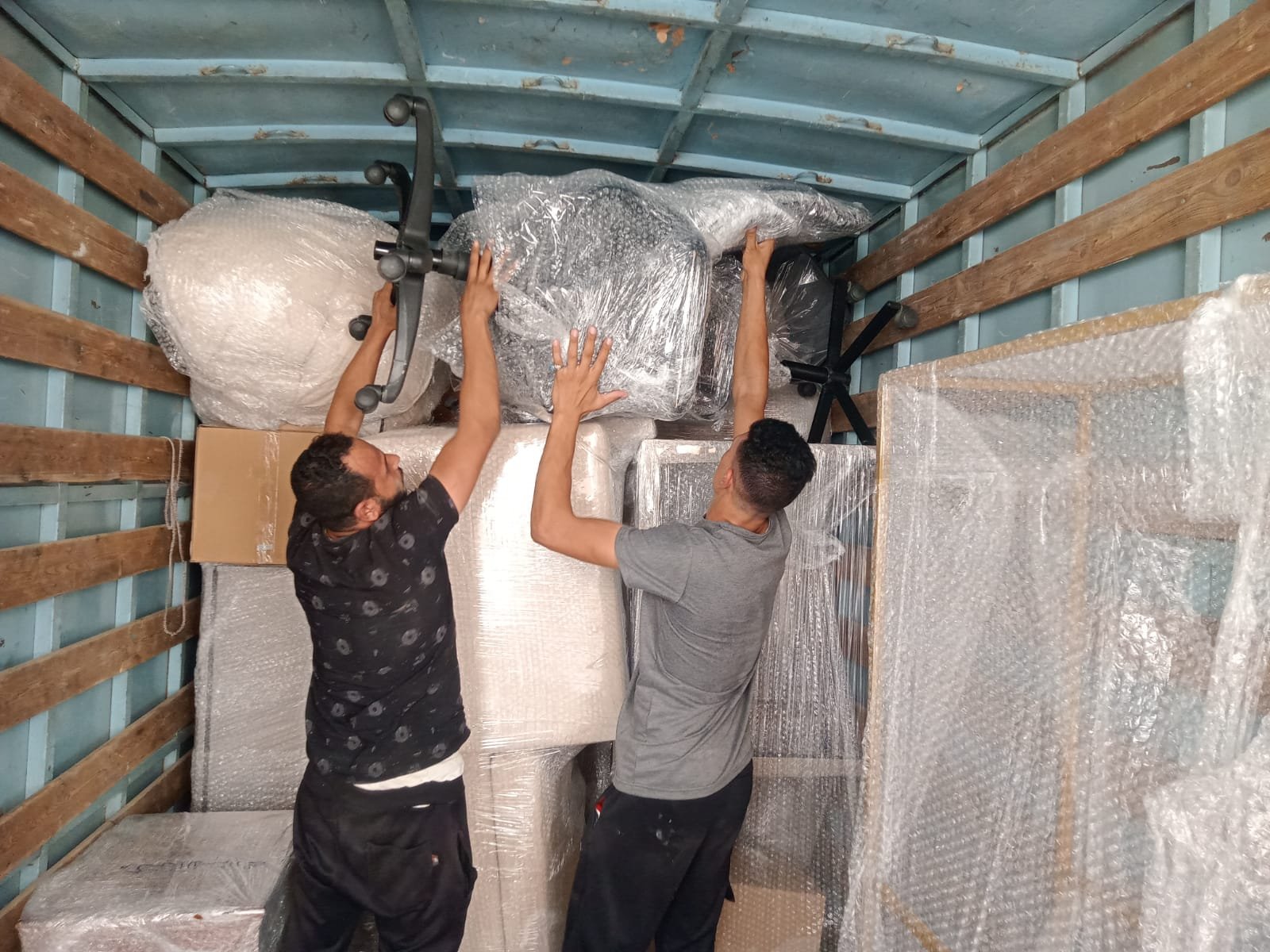فريق عمل شركة خيال يرص الأثاث المغلف بعناية داخل الشاحنة